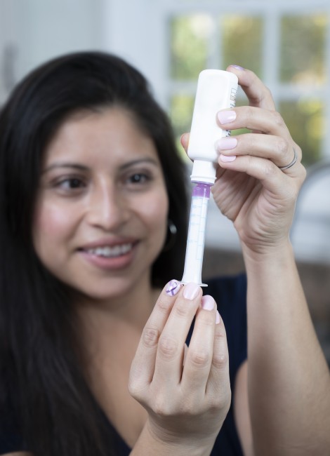 Hispanic/Latinx woman with dark hair measuring medicine with syringe